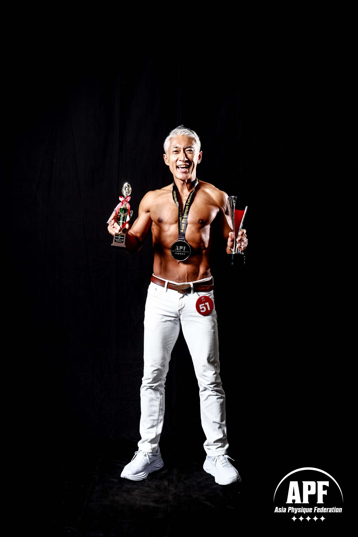 The image features a man with trophies, likely from a bodybuilding competition, set against a black background. The man ha...